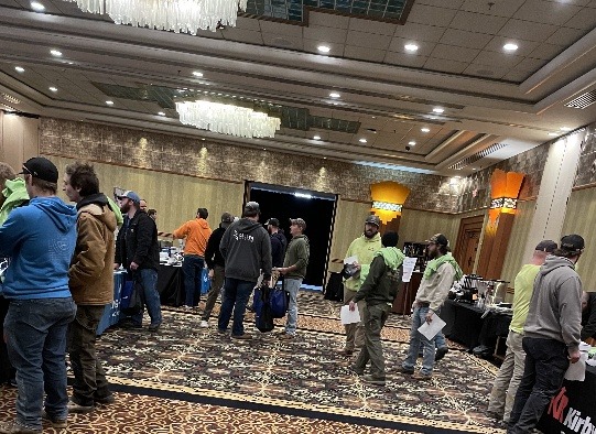 A group of people gathered around tables in a spacious room, engaged in conversation and activities.