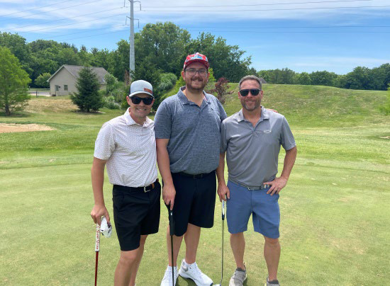 Three men in casual polo shirts posing together.